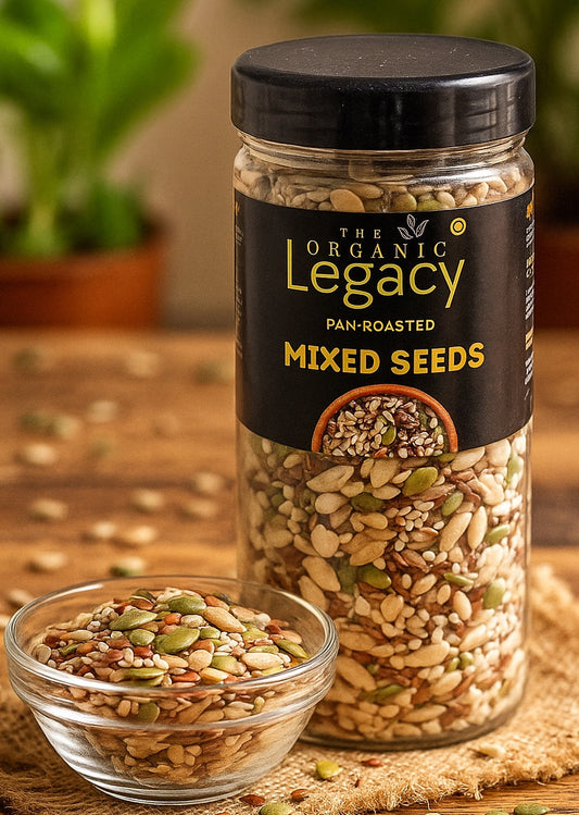 Jar of 'The Organic Legacy' mixed seeds on a wooden surface with a small bowl of seeds.